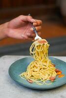 the hand that is lifting the spaghetti on the plate photo
