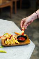 cropped hand dipping potato slice to sauce close up photo