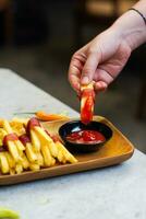 cropped hand dipping potato slice to sauce close up photo