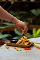 cropped hand dipping potato slice to sauce close up photo