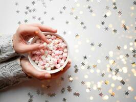 cup with marshmallows on a white background with silver snowflakes photo