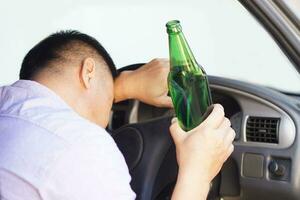 Drunk man holds beer bottle in car. Concept, Stop driving while drinking alcohol beverage or whiskey campaign. Illegal and dangerous to drive vehicle that leads to accident photo