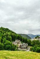 a green hillside with houses in the distance photo