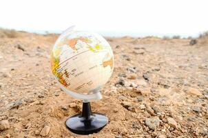 a globe on a stand in the middle of a desert photo