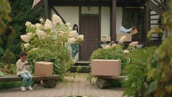 A multi-ethnic family is moving into a new home and carrying things in boxes. African dad, Caucasian mom, son. video