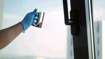 hand in blue rubber gloves cleaning window video