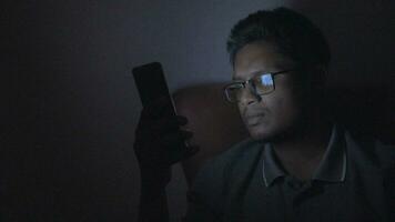 young men using smart phone at night sitting on sofa at home video