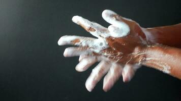 young man washing hands with soap warm water against black background video