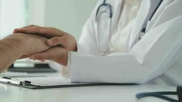 Doctor reassuring patient sitting and discussing something near each other at the white desk in clinic, close up. Empathy in medicine concept video