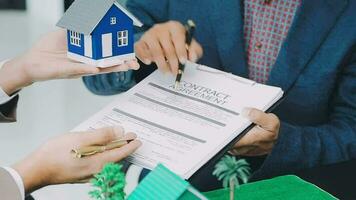 agente di intermediazione immobiliare che presenta e consulta al cliente per prendere decisioni firmare un contratto di assicurazione, modello di casa, riguardante l'offerta di mutuo ipotecario e l'assicurazione sulla casa. video