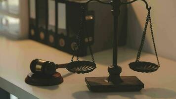 Business and lawyers discussing contract papers with brass scale on desk in office. Law, legal services, advice, justice and law concept picture with film grain effect video