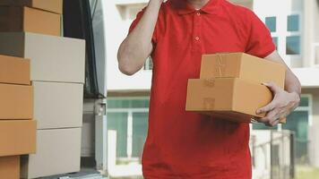 Fast and reliable service. Cheerful young delivery man giving a cardboard box to young woman while standing at the entrance of her apartment video