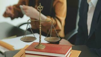 Business and lawyers discussing contract papers with brass scale on desk in office. Law, legal services, advice, justice and law concept picture with film grain effect video