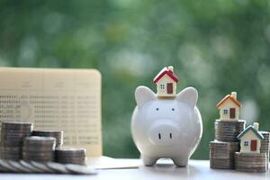 modelo casa en cerdito banco con apilar de monedas dinero en naturaleza verde antecedentes,negocios inversión y real inmuebles concepto foto