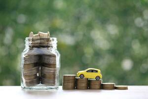 modelo de coche en miniatura en la creciente pila de monedas dinero en el fondo verde de la naturaleza, ahorrando dinero para el coche, finanzas y préstamo de coche, inversión y concepto de negocio foto