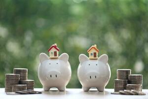 Model house on piggy bank with stack of coins money on nature green background,Business investment and real estate concept photo