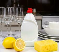 Detergent with lemon and sponge on the table in the kitchen. Cleaning concept. Mockup. Close-up. Selective focus. photo