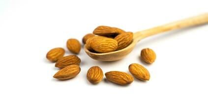 Banner. Dried almonds in wooden spoon isolated on white background. Close-up. Copy space. photo