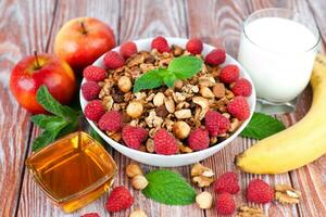 A bowl of granola and fresh raspberries on a wooden background. Healthy breakfast concept. photo