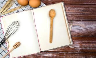 blanco Clásico receta libro, huevos y cuchara en el de madera antecedentes. parte superior vista. sitio para texto. bandera. foto