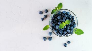 Fresh ripe blueberries in a glass bowl on grey background. Top view. Copy space. photo