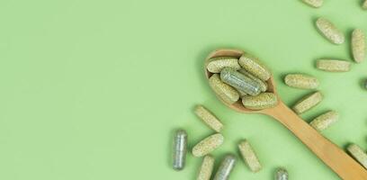 Vitamins and Supplements in a spoon on a green background. Top view. Close-up. Copy space. photo