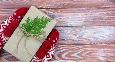 Women's hands in winter gloves hold DIY Christmas gift. Top view. Copy space. Close-up. photo