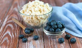 Fresh blueberries and cottage cheese on the wooden background. Selective focus. Healthy breakfast in the morning. Close-up. photo