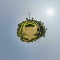 coconut trees in jungle in Indian tropic village on sea shore on little planet in evening sky, transformation of spherical 360 panorama. Spherical abstract view with curvature of space. photo