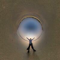 blue hole sphere little planet inside ocean seashore and sands withhappy man stands on coast in rays of evening tropical sun with transformation of spherical panorama 360 degrees. urvature of space. photo