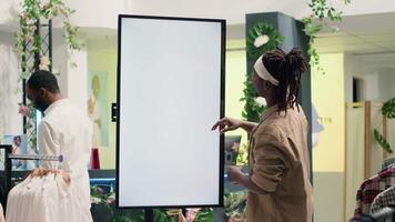 African american man in clothing store using augmented reality mockup screen to look at garment options to try on. Customer using led display to visualize fashion choices in showroom video