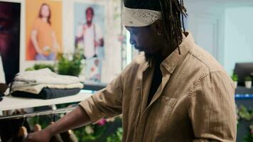 Tracking shot of customer in clothing store during promotional season looking to purchase cheap garments. Client taking advantage of sales in fashion boutique, looking at clothes on racks video