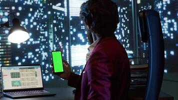 Qualified consultant operates on famous global company while looking at mobile device with greenscreen interface. In skyscraper office building, business leader checks isolated copyspace display. video