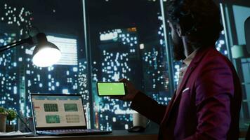 företag ägare använder sig av grönskärm på smartphone visa, Sammanträde på hans lyx skrivbord i skyskrapa och arbetssätt på företag utveckling. finansiell expert- utseende på tom Chromakey mockup. video