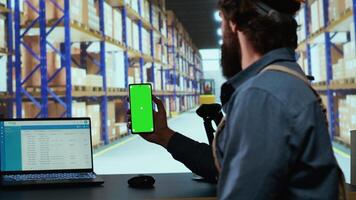 Delivery industrial advisor shows greenscreen display in warehouse storage room, working on cargo logistics for new order shipment. Depot supervisor holds isolated chromakey device. video