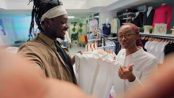 Content creator and employee browsing through wares in thrift shop with vintage clothes, presenting hidden gems. Influencer showcasing premium second hand clothing store high street garments photo