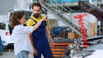 Serviceman in car service using holographic augmented reality to show customer defective vehicle piston. Hardworking garage employee using innovative AR tech to project automobile parts for woman photo