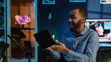 African american technology internet star filming review of newly released graphic tablet, greeting audience and presenting them feedback about touchscreen sensitivity, doing endorsement photo