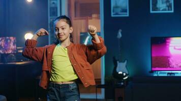 Close up shot of energetic joyful kid doing charming dance moves for social media platform, following viral challenge. Joyous child recording video for online followers in dimly lit house photo