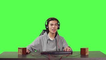 POV of player competing at video games on computer while speaking on headphones to his friends, playing interactive combat challenge at desk. Asian gamer having fun with his free time.