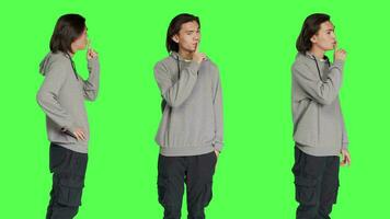 Person doing mute silence symbol over greenscreen, expressing secrecy gesture with finger over lips. Young adult showing hush sign, being private in studio with blank backdrop. video