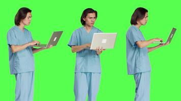 specialista lettura paziente informazione su computer portatile, utilizzando senza fili computer prima di partenza assistenza sanitaria verifica. giovane uomo Lavorando come medico assistente, utilizzando portatile pc su schermo verde. video