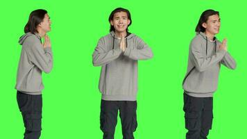 persoon houden handen in een gebed naar vragen Jezus voor mooi zo geluk, gevoel religieus en bidden tegen groene scherm geïsoleerd sjabloon. religieus Aziatisch vent acteren hoopvol in studio. video