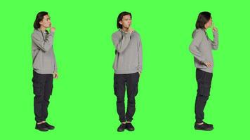 Adult doing hush secret sign over greenscreen, expressing secrecy symbol with finger over lips. Young person showing mute silence gesture , being private in studio with full body backdrop. video