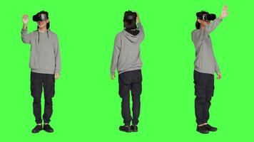 ung vuxen åtnjuter virtuell verklighet grej i studio med grönskärm bakgrund, använder sig av interaktiv syn eller simulering på headset. modern kille har roligt med artificiell intelligens vr glasögon. video