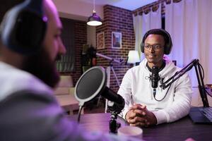 Podcast presenter having live conversation with man, recording discussion for audience on internet entertainment show. Influencer enjoying chat with guest, broadcasting at home photo