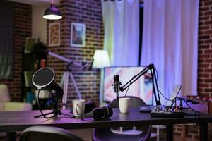 Empty home production studio with podcast equipment technology recording sound for streaming site entertainment show. Live broadcasting cozy location in living room with rgb lights photo