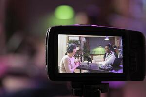 Close up shot focused on preview image on professional camera with podcast host and african american guest enjoying conversation in blurry background. Professional recording equipment in home studio photo