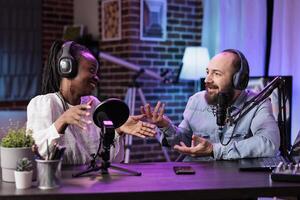 Experienced host engaging in entertaining dialogue with celebrity during live stream in professional studio. Presenter using high quality cameras, microphones and RGB lights to enhance production photo