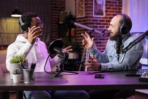 Skillful host engaging in entertaining discussion with celebrity during live stream in professional studio. Presenter using high quality cameras, microphones and neon lights to enhance online show photo